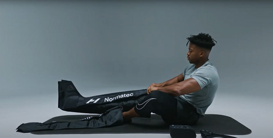 Sliding each leg into the Normatec boots and zipping them up